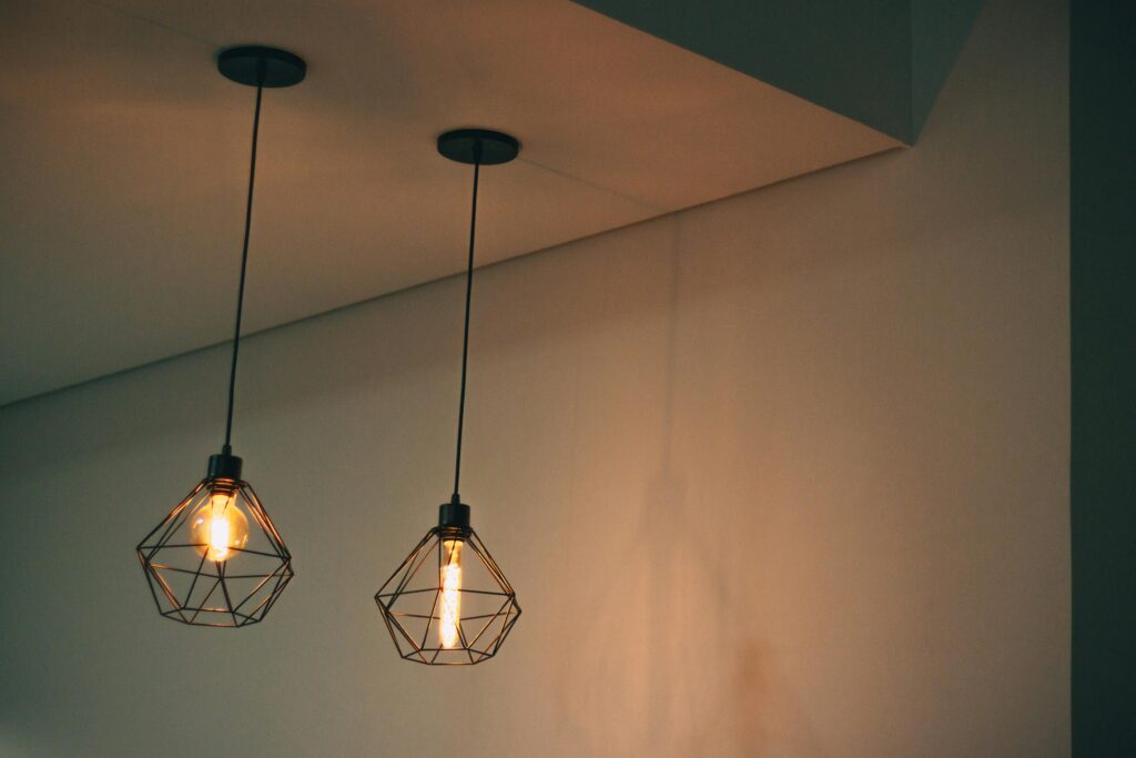 Stylish geometric pendant light fixtures casting warm light in a minimalistic indoor setting.